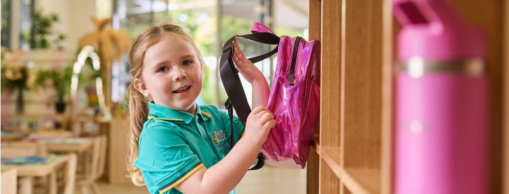 How Busy Bees Supports School Readiness A young girl who is preparing for school is placing a bag into a school shelf
