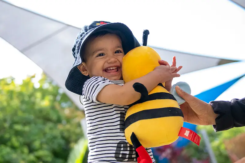 Preschool child cuddling bee soft toy
