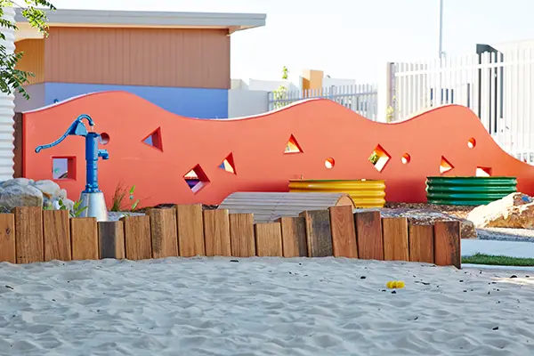 outdoor playground with sandpit and garden beds at Crace childcare