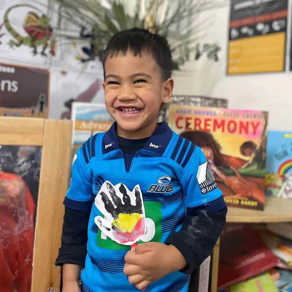 Kindergarten boy holding painting with Aboriginal flag colours