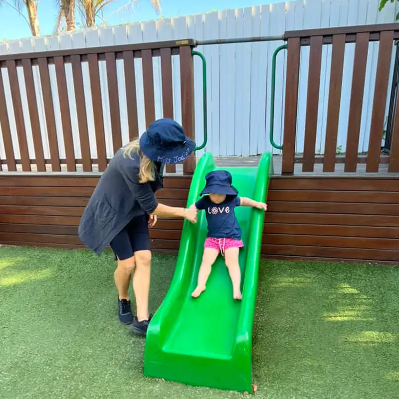 Educator assisting a child down a slide at Underwood childcare centre