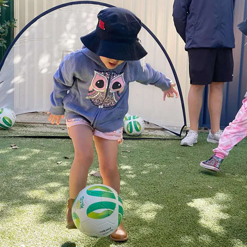 Preschool girl kicking a soccer ball