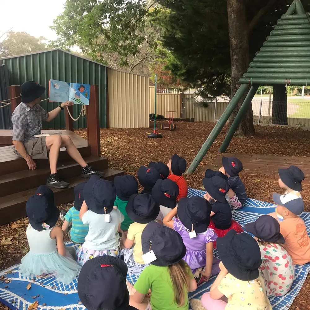 Early Childhood Educator reading a book to preschool children at Curtin child care centre