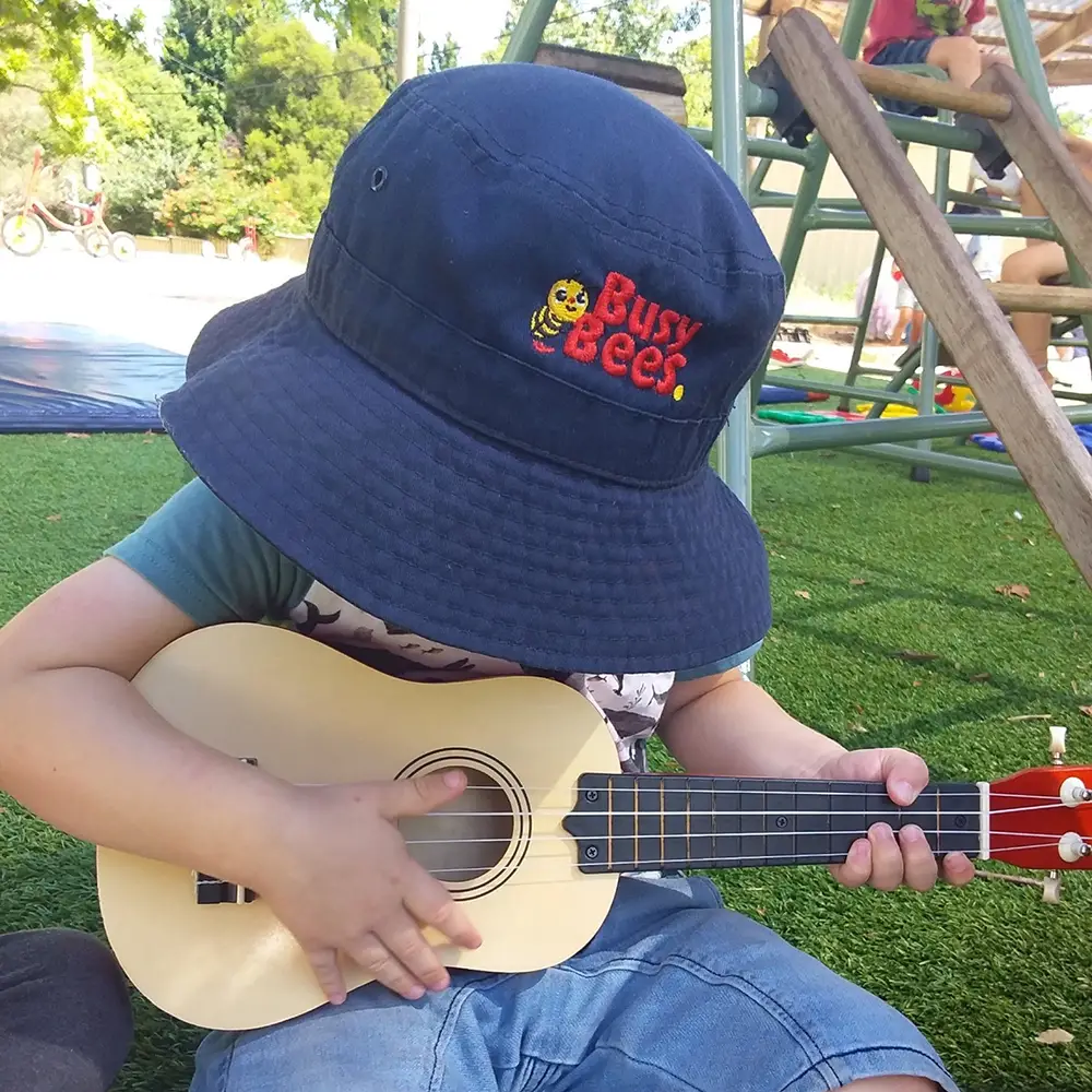Preschool child playing a ukulele at Curtin childcare