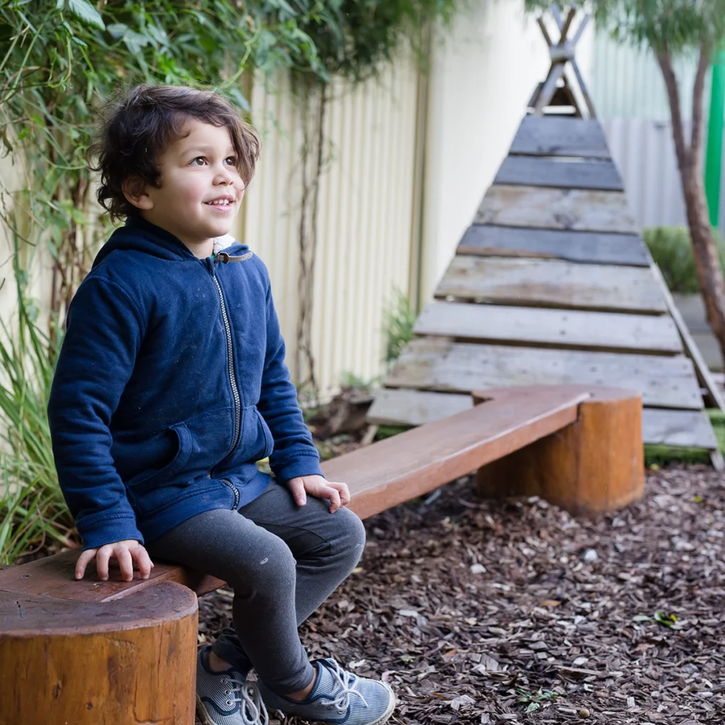 Preschool boy sitting on balance beam at childcare in City of Stirling