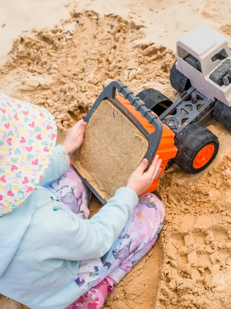 Child playing with bulldozer in sandpit