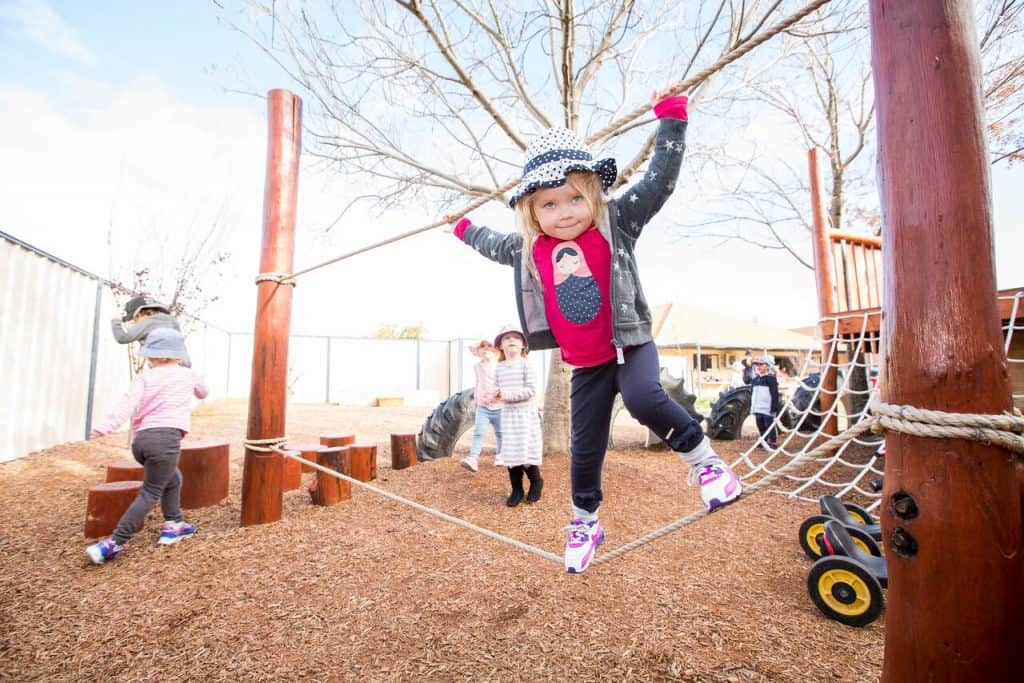 Girl on rope bridge in day care playground