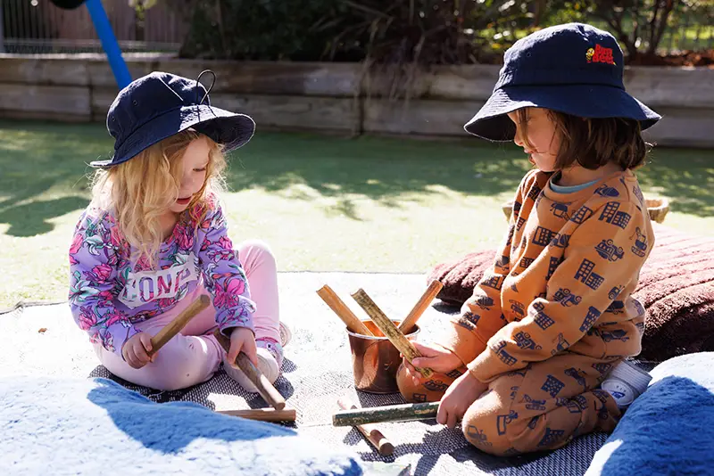 Two girls using wooden clapping sticks