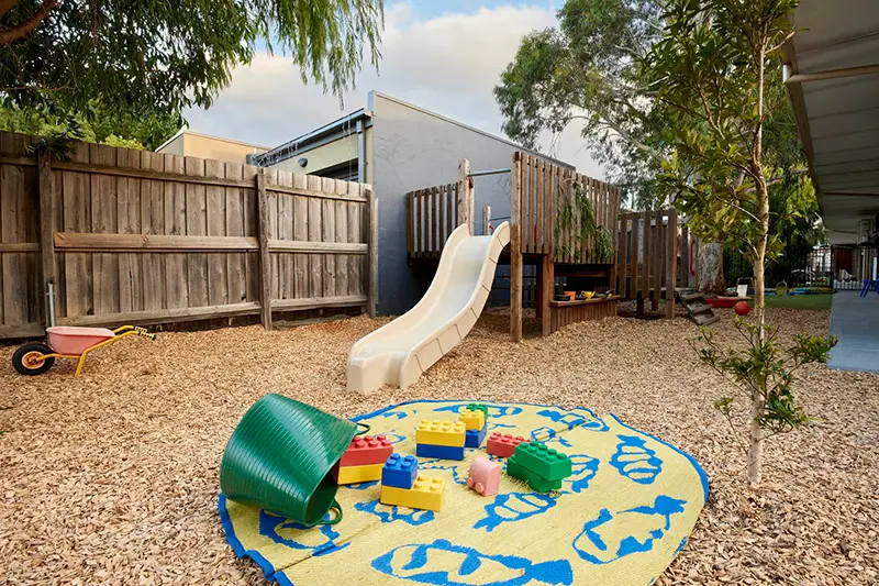 Playground slide and day care toys on mat