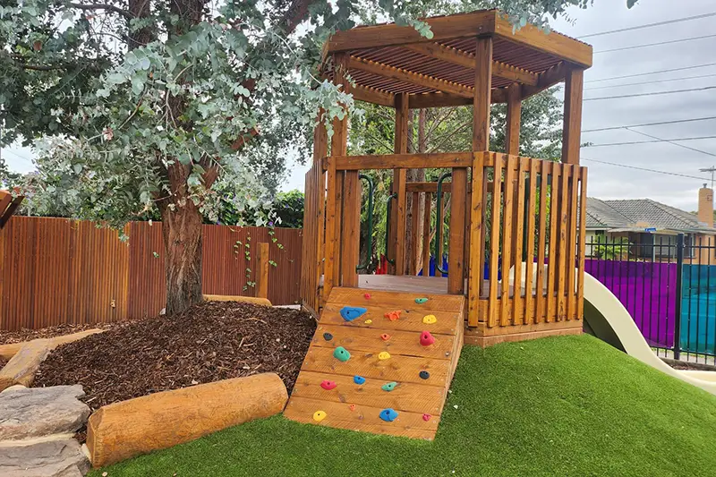 Timber fort with slide and climbing wall in the outdoor playground at Lalor childcare