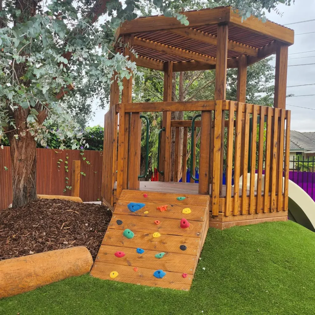 Timber fort with slide and climbing wall in the outdoor playground at Lalor childcare