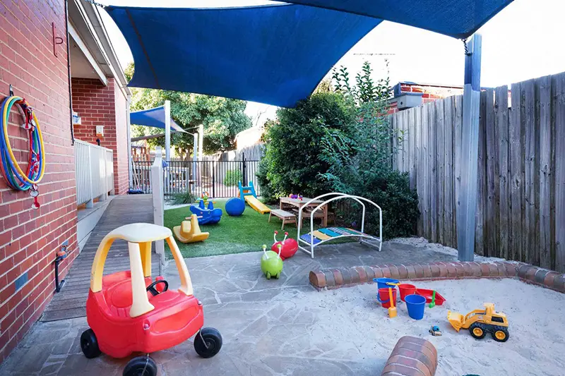 Nursery day care playground with sandpit and red ride-on car