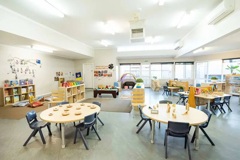 Preschool room with activity tables and reading area.