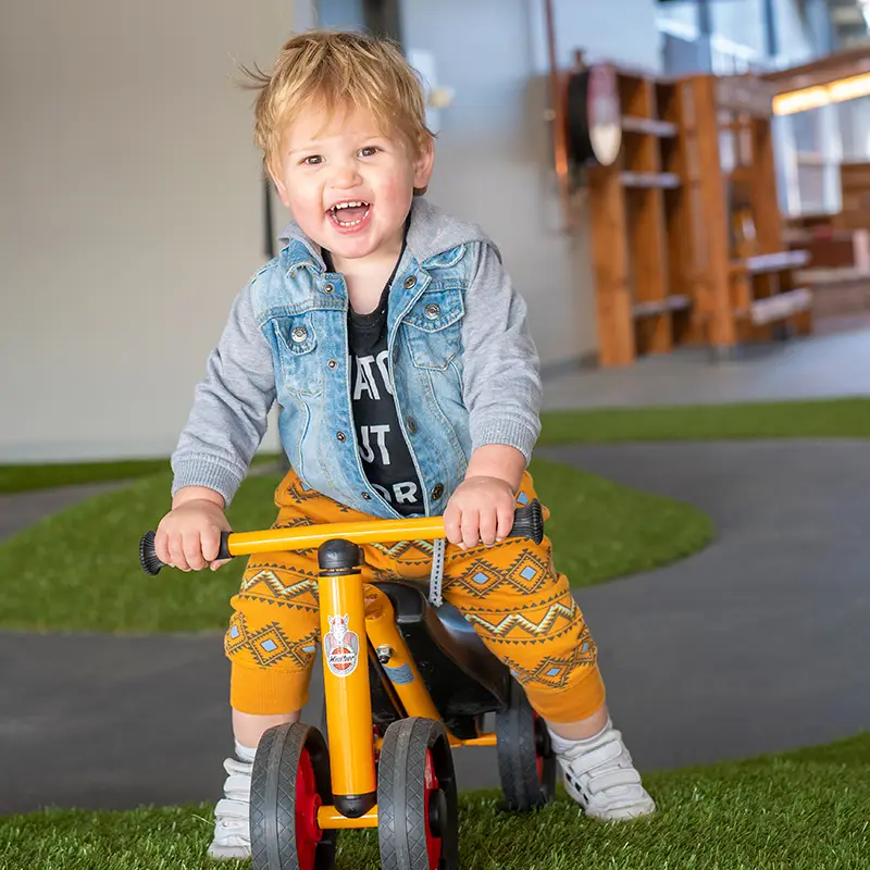 toddler boy riding tricycle in playground at Shepparton childcare