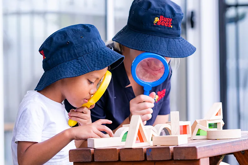 Busy Bees Early Childhood Educator and child looking through magnifying glasses