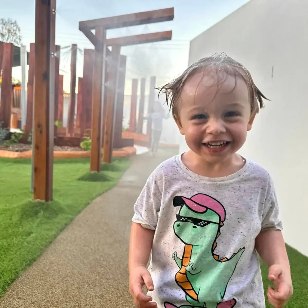 Child running through water misters at Everton Hills childcare centre