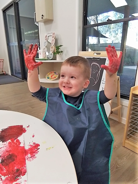 Child with red paint on hands