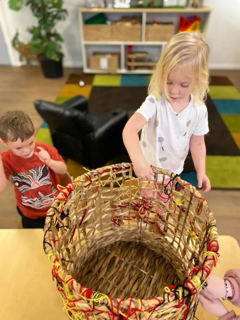 Child weaving Aboriginal indigenous colours on basket
