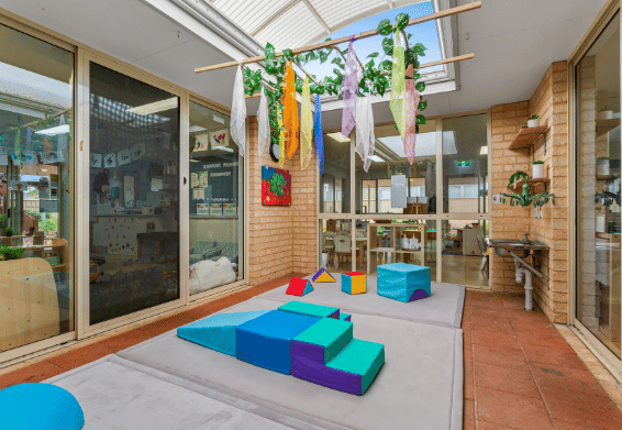 Covered outdoor learning area with soft play equipment.