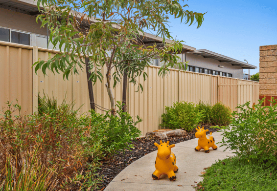 Garden pathway with native plants and outdoor play ride on toys.