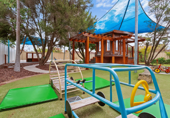 Outdoor playground with climbing equipment and shade sails.