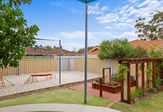 Outdoor playground with open grassed areas and play equipment.