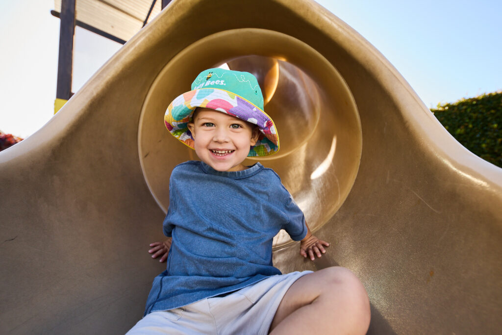 Child sitting inside a playground tunnel during outdoor play.