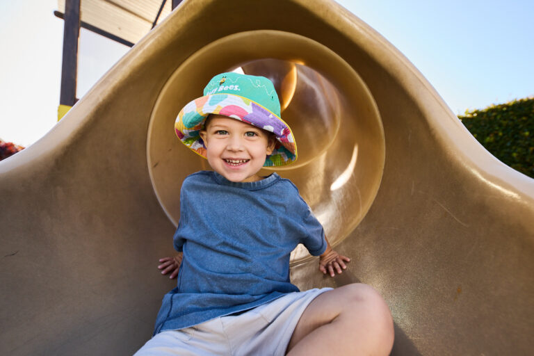 Child sitting inside a playground tunnel during outdoor play.