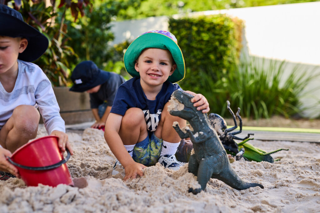 Child playing outdoors in a sand and nature play environment.