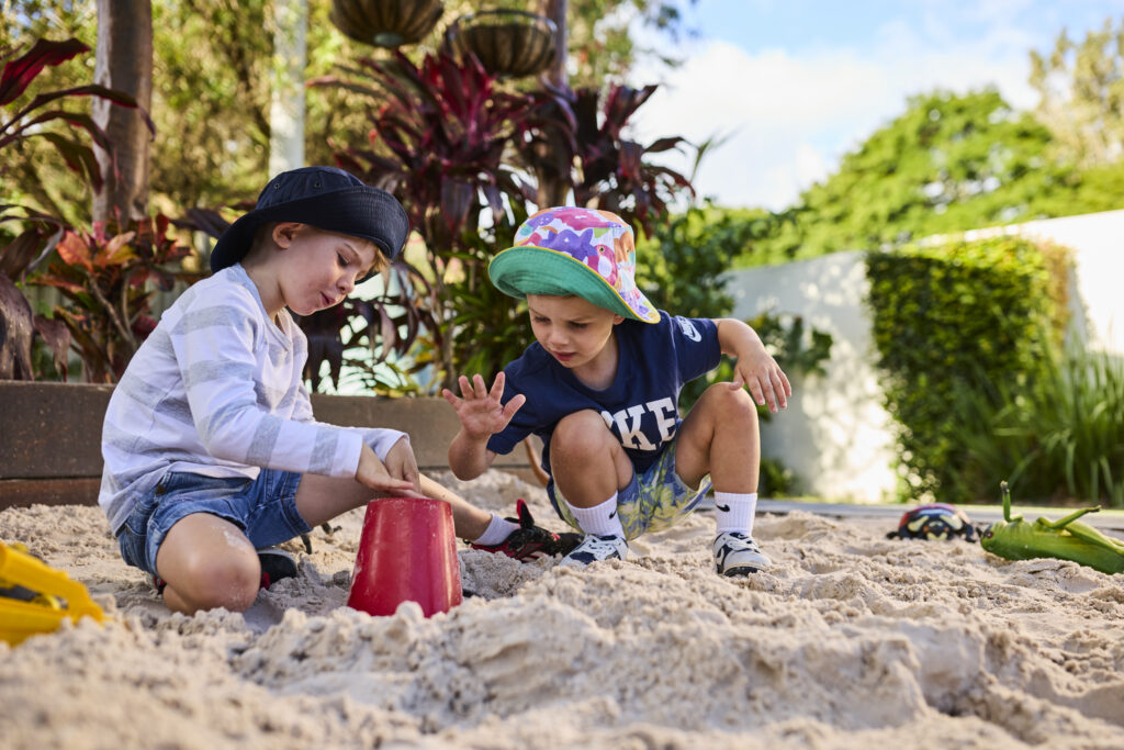Children playing together in a sandpit at a Busy Bees early learning centre outdoor playground.
