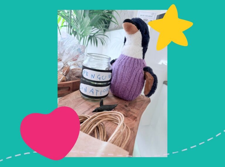 Bubbles the Penguin wearing one of the knitted jumpers holding the Penguin tip jar