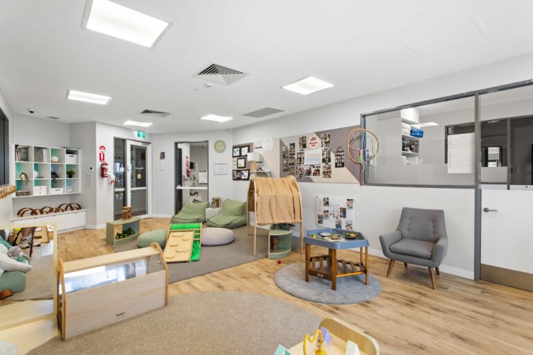 Nursery room at Busy Bees Aveley with soft play, a feeding armchair and a documentation wall