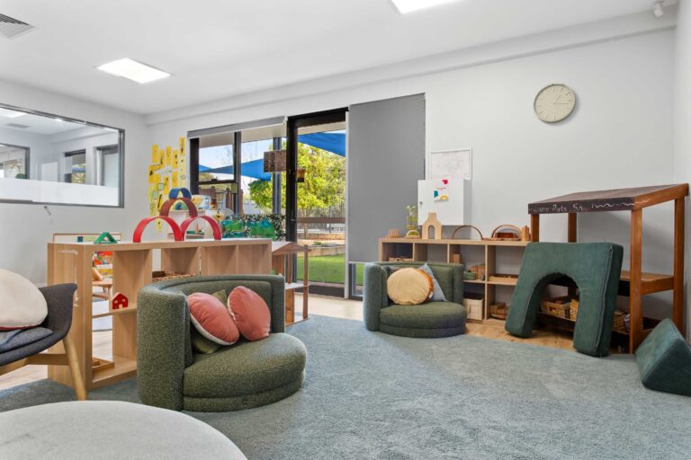 Soft play area at Busy Bees Aveley with floor cushions, low shelving and windows to the garden