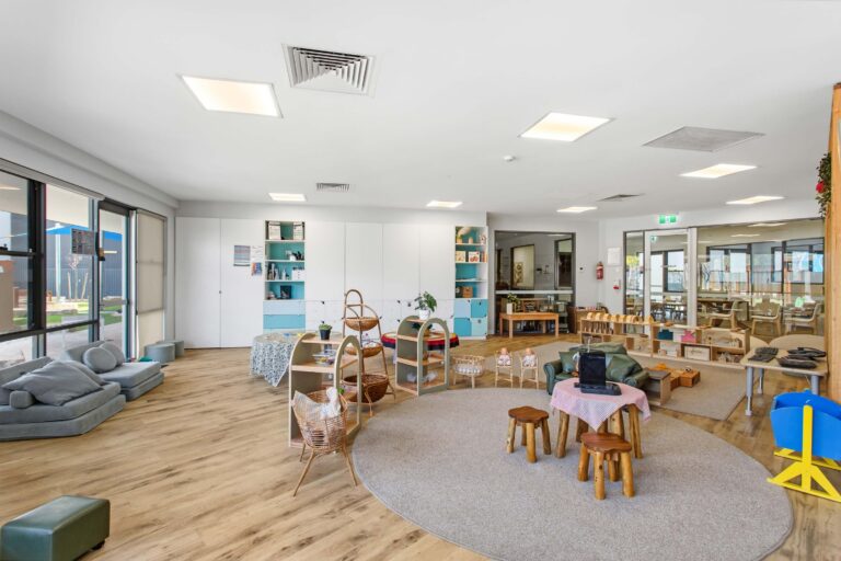 Toddler room at Busy Bees Aveley with floor cushions, a round rug and arched display frames