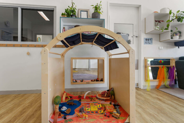 Timber arch cubby with a mirror and small world play mat at Busy Bees Banksia Grove Village