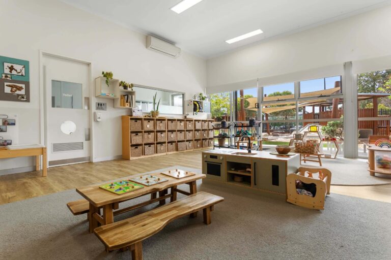 Kindergarten room at Busy Bees Banksia Grove Village with timber picnic tables and windows to the playground