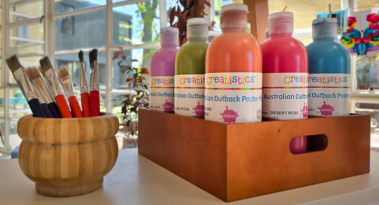 Poster paints and brushes set out for an art experience at Busy Bees Moonee Valley