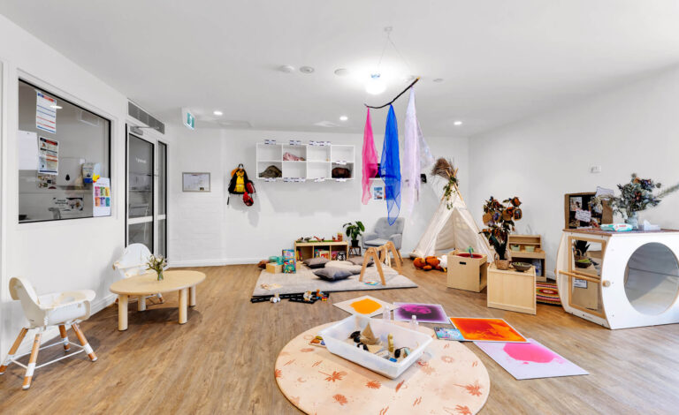 Nursery room at Busy Bees Moonee Valley with a play teepee, timber play gym and soft floor cushions