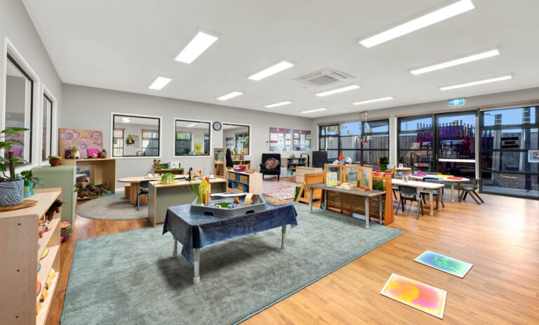 Kindergarten room at Busy Bees Truganina with timber furniture, art area and doors opening to the garden